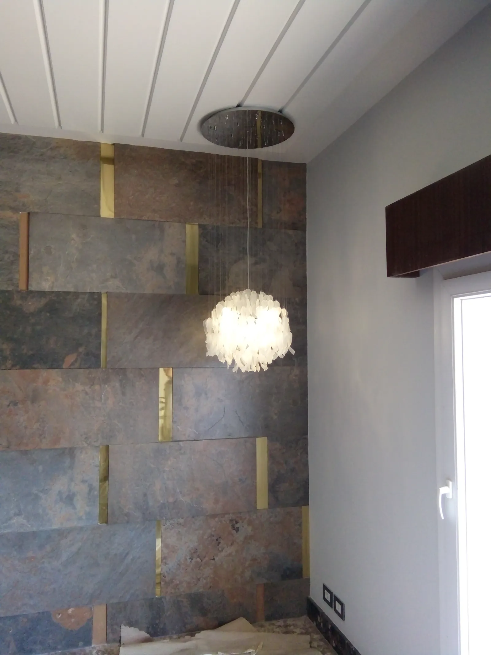 Reception lobby with slate feature wall and feather-cluster chandelier, finished by Eldora